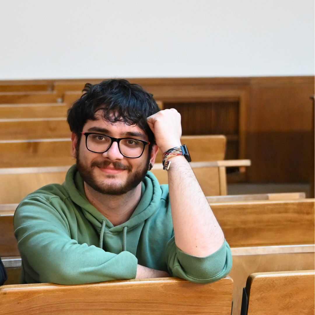 Picture of Simone Ramello, sitting in some university room and leaning on the desk.