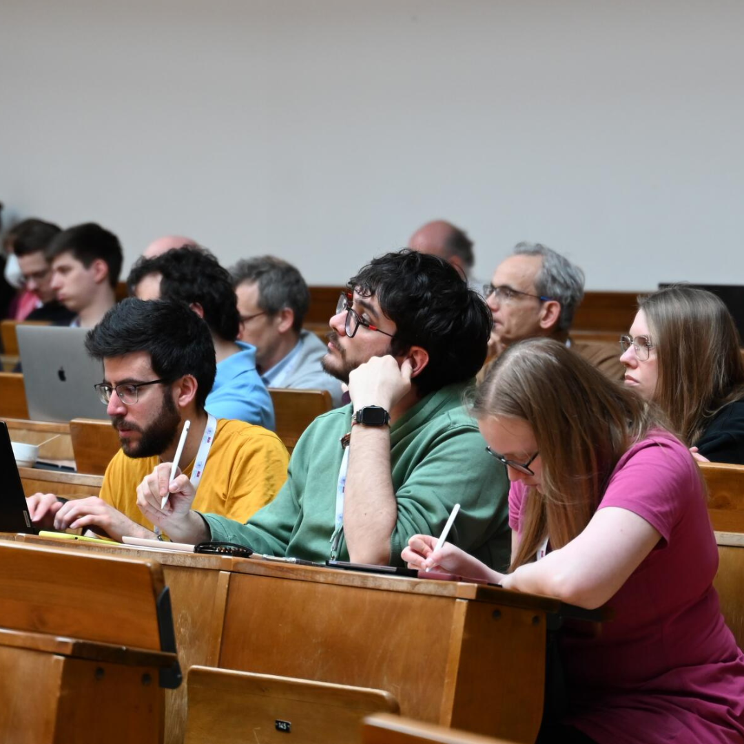 Picture of three people taking notes during a talk.